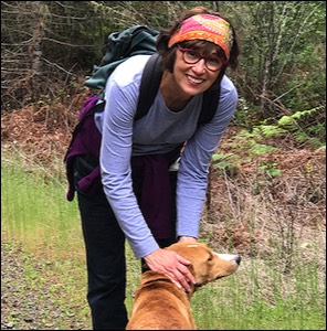 Woman with backpack leaning over dog