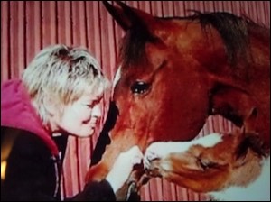 Woman kissing mare with foal