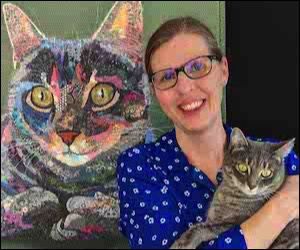 Woman with cat in arms and cat tapestry in background