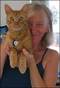 Woman holding orange tabby next to her face